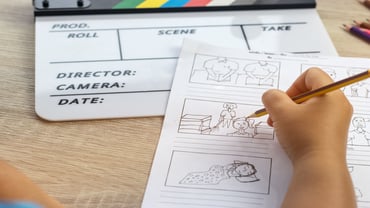 Person writing a video script with a slate board sitting on a table 
